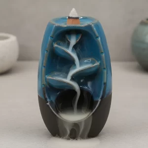 Fuente cascada de humo para incienso tipo backflow con efecto visual relajante. Incluye 20 conos surtidos. Ideal para meditación, yoga, aromaterapia y armonización de espacios. Medidas: 13 x 8 cm.